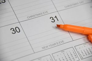 an orange marker is laying on a calendar showing December 31 and the words New Years Eve